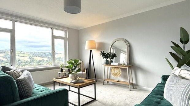 A repainted and styled living room with a green sofa and a valley view through the window